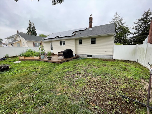39 Herbert Ave, Lindenhurst, NY 11757 - back of property with a fenced backyard, roof mounted solar panels, a deck, and a chimney