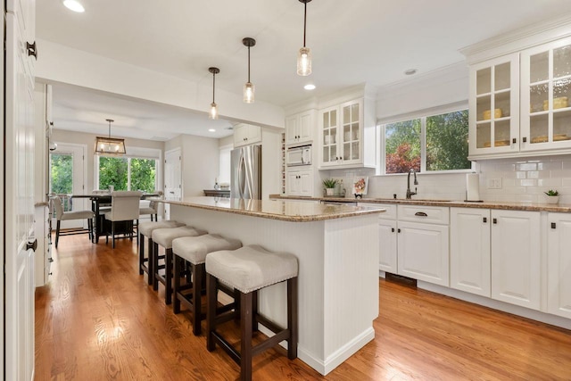 9 Carol Ct, Brewster, NY 10509 - kitchen with freestanding refrigerator, white microwave, light wood finished floors, a breakfast bar area, and light stone counters