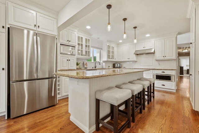 9 Carol Ct, Brewster, NY 10509 - kitchen featuring stainless steel refrigerator, under cabinet range hood, a warming drawer, white cabinets, and white microwave