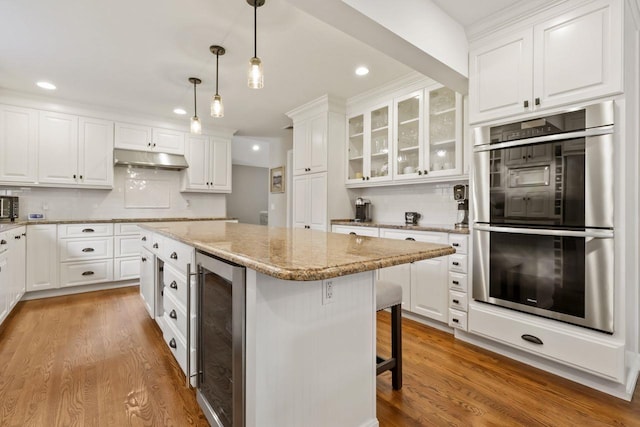 9 Carol Ct, Brewster, NY 10509 - kitchen featuring double oven, wine cooler, a breakfast bar area, white cabinetry, and recessed lighting