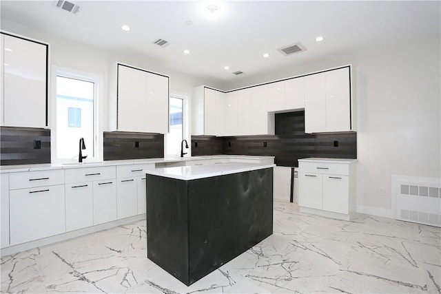 33 Ewing Ave Unit 102, Spring Valley, NY 10977 - kitchen featuring modern cabinets, backsplash, a kitchen island, white cabinets, and light marble finish floors
