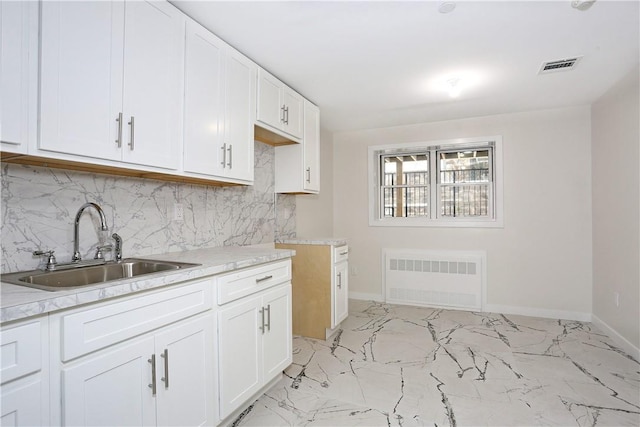 33 Ewing Ave Unit 102, Spring Valley, NY 10977 - kitchen featuring radiator, decorative backsplash, light countertops, white cabinets, and light marble finish floors