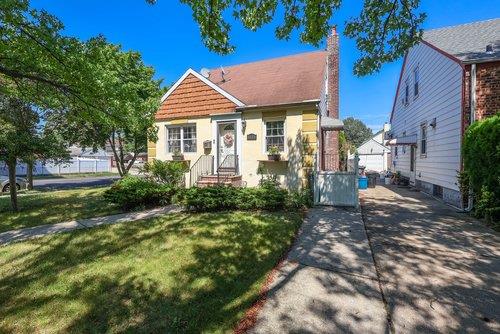 46-03 195th St, Flushing, NY 11358 - bungalow featuring a front yard, a chimney, entry steps, and stucco siding