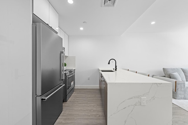 46-40 Vernon Blvd Unit 2A, Long Island City, NY 11101 - kitchen with stainless steel appliances, a peninsula, white cabinets, recessed lighting, and light wood-type flooring