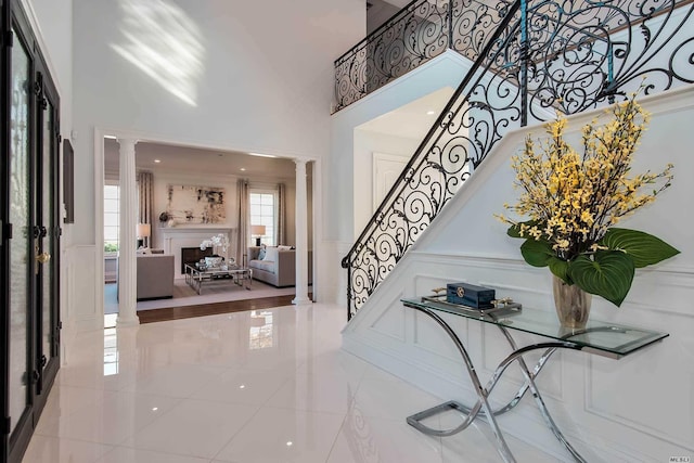 272 Crabapple Rd, Manhasset, NY 11030 - tiled entrance foyer with ornate columns, a towering ceiling, stairs, and a decorative wall