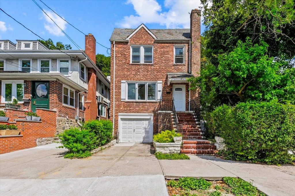 6112 Fieldston Rd, Bronx, NY 10471 - view of front facade featuring concrete driveway, an attached garage, brick siding, and a chimney