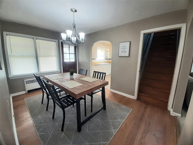 52 Fountain Pl, Poughkeepsie, NY 12603 - dining room featuring radiator, arched walkways, a chandelier, dark wood-type flooring, and stairs