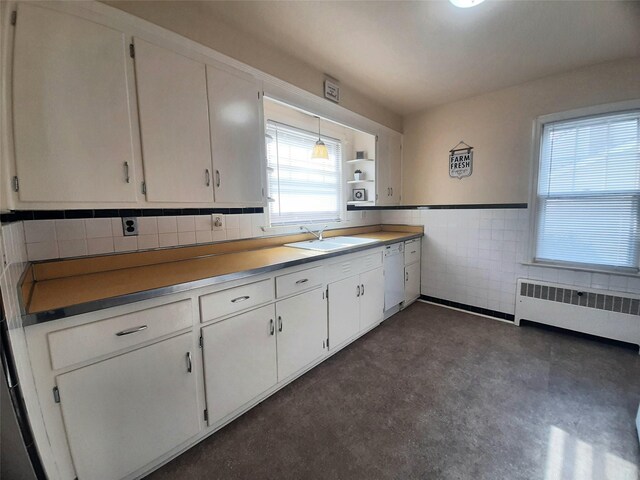 52 Fountain Pl, Poughkeepsie, NY 12603 - kitchen featuring radiator, white cabinetry, dishwasher, tile walls, and concrete flooring