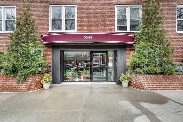 50-22 40th St Unit 2F, Sunnyside, NY 11104 - doorway to property featuring concrete driveway, brick siding, and a garage
