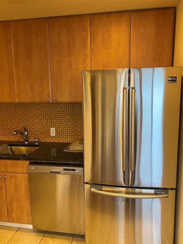 3138 137th St Unit 9B, Flushing, NY 11354 - kitchen featuring appliances with stainless steel finishes, light tile patterned floors, brown cabinetry, tasteful backsplash, and dark stone counters