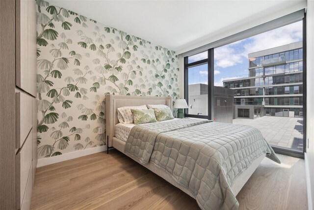 38-20 Parsons Blvd Unit 215, Flushing, NY 11354 - bedroom featuring wallpapered walls, wood finished floors, an accent wall, and a wall of windows