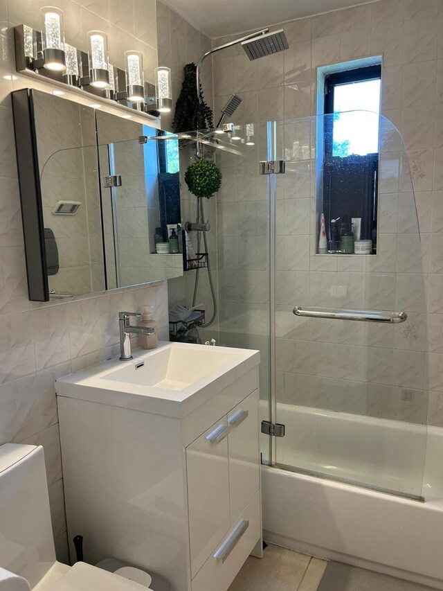 150-10 71st Ave Unit 2G, Kew Garden Hills, NY 11367 - full bathroom with tile walls, vanity, bath / shower combo with glass door, and tile patterned flooring