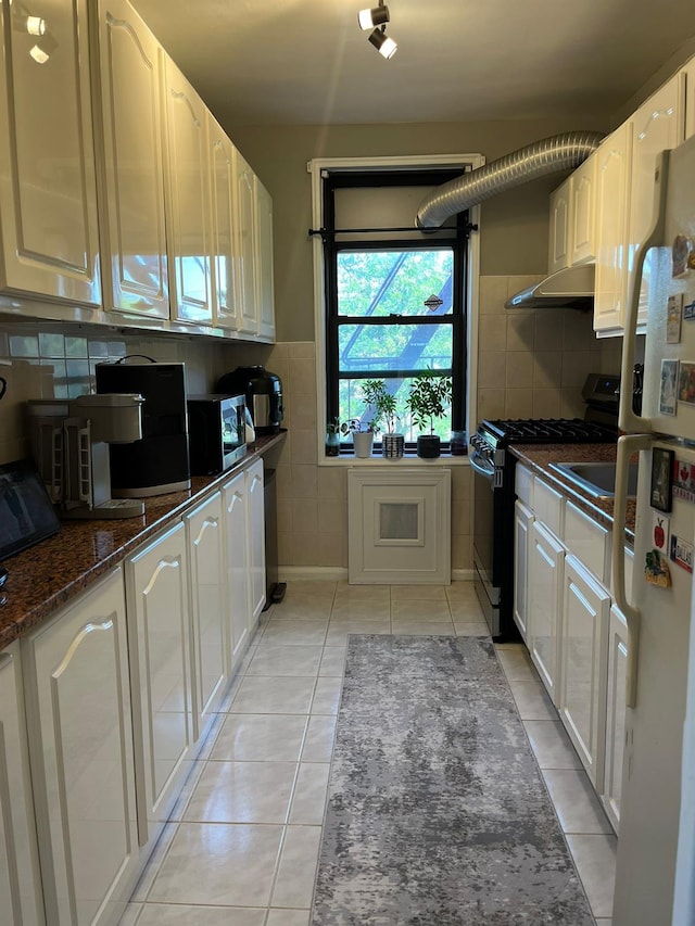 150-10 71st Ave Unit 2G, Kew Garden Hills, NY 11367 - kitchen with gas range oven, freestanding refrigerator, light tile patterned flooring, extractor fan, and white cabinetry