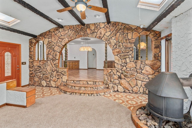 60 Wheatfield Ln, Commack, NY 11725 - unfurnished living room featuring a skylight, a wood stove, arched walkways, a ceiling fan, and carpet floors