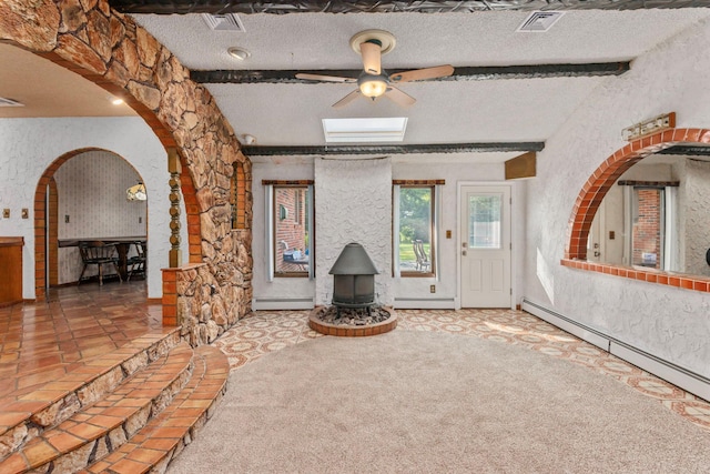60 Wheatfield Ln, Commack, NY 11725 - unfurnished living room featuring a wood stove, a baseboard heating unit, ceiling fan, a textured ceiling, and arched walkways