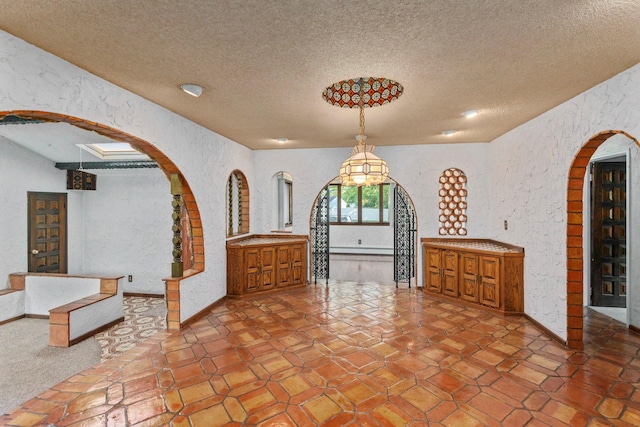 60 Wheatfield Ln, Commack, NY 11725 - unfurnished dining area featuring arched walkways, a textured ceiling, and a textured wall