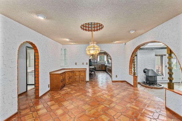 60 Wheatfield Ln, Commack, NY 11725 - unfurnished dining area featuring a textured wall, a textured ceiling, arched walkways, and a wood stove