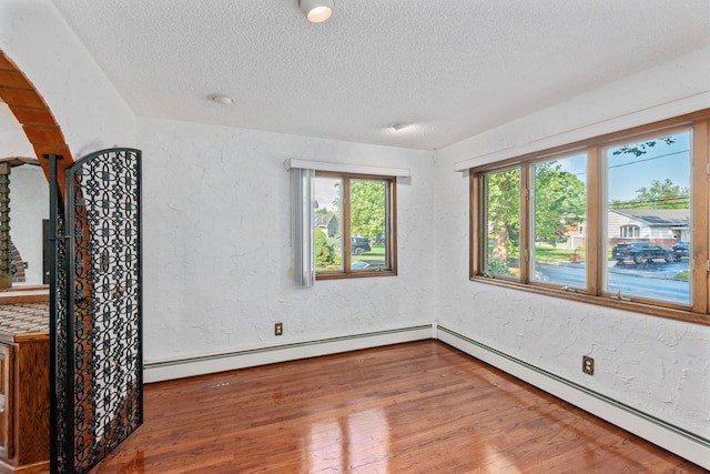 60 Wheatfield Ln, Commack, NY 11725 - spare room with a baseboard heating unit, a textured ceiling, wood finished floors, and a textured wall