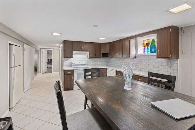 60 Wheatfield Ln, Commack, NY 11725 - kitchen with white appliances, under cabinet range hood, light tile patterned floors, backsplash, and dark brown cabinets