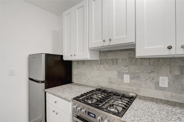 123-25 82nd Ave Unit 5R, Kew Gardens, NY 11415 - kitchen featuring stainless steel gas stove, white cabinetry, freestanding refrigerator, decorative backsplash, and light stone countertops