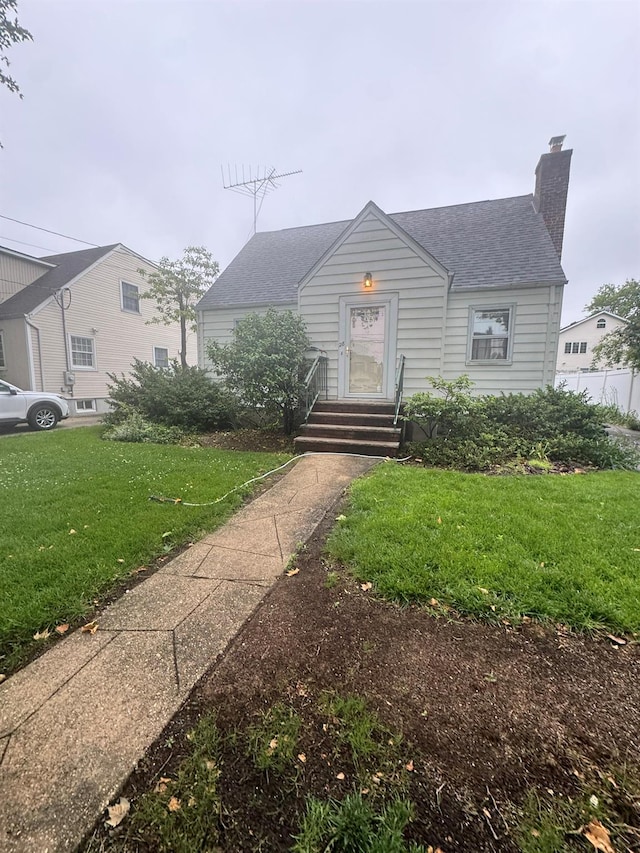28 Ruxton St, New Hyde Park, NY 11040 - bungalow-style house featuring a front lawn, roof with shingles, a chimney, and entry steps