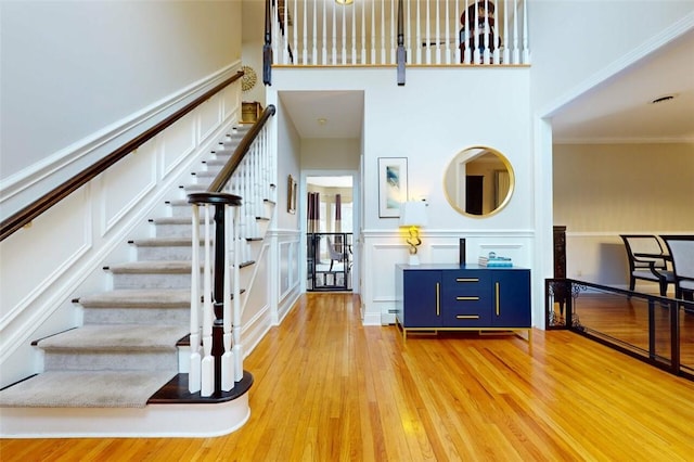 9 Roselawn Rd, Highland Mills, NY 10930 - stairs featuring wood finished floors, a towering ceiling, a decorative wall, crown molding, and wainscoting