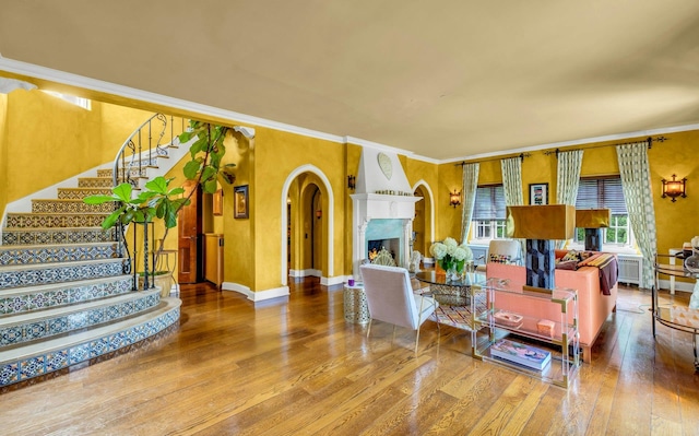 259 Lakeview Ave W, Brightwaters, NY 11718 - living area with wood finished floors, ornamental molding, stairway, a lit fireplace, and arched walkways