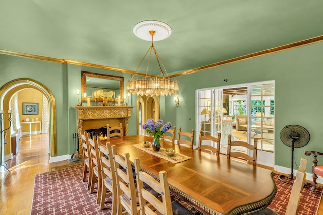 259 Lakeview Ave W, Brightwaters, NY 11718 - dining room featuring arched walkways, crown molding, wood finished floors, a warm lit fireplace, and a chandelier