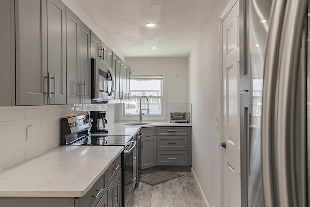 57 7th St, Pelham, NY 10803 - kitchen featuring stainless steel appliances, gray cabinetry, backsplash, light wood finished floors, and recessed lighting