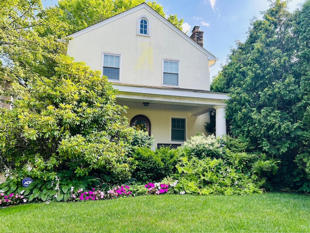 46 Beechwood Ter, Yonkers, NY 10705 - view of front of home with stucco siding, a chimney, and a front lawn