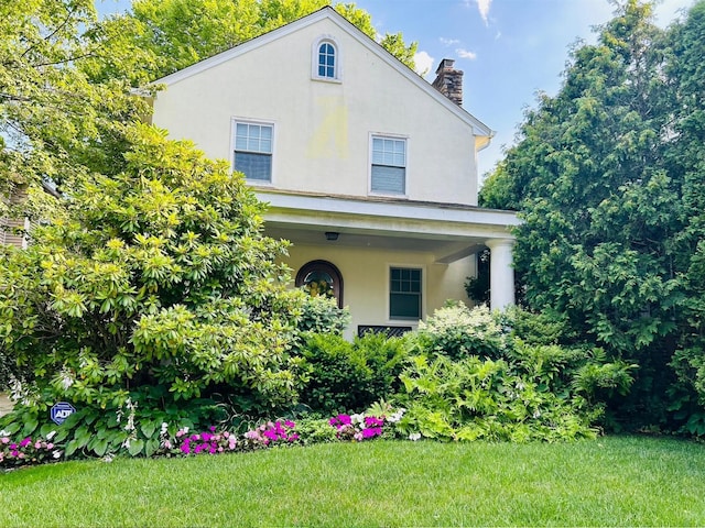 46 Beechwood Ter, Yonkers, NY 10705 - view of front of home with stucco siding, a chimney, and a front lawn