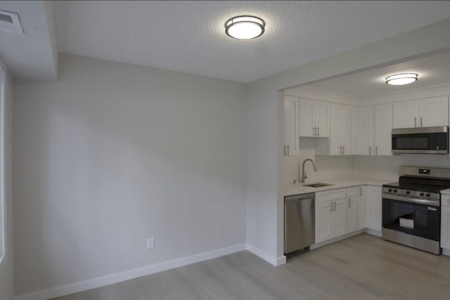227 Springmeadow Dr Unit E, Holbrook, NY 11741 - kitchen with stainless steel appliances, light wood finished floors, white cabinets, and a textured ceiling