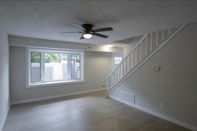 227 Springmeadow Dr Unit E, Holbrook, NY 11741 - unfurnished living room with wood finished floors, ceiling fan, stairs, and a textured ceiling
