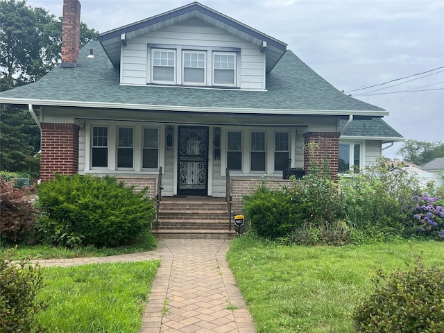 221 E Dean St, Freeport, NY 11520 - bungalow-style house with a porch, a shingled roof, brick siding, and a chimney