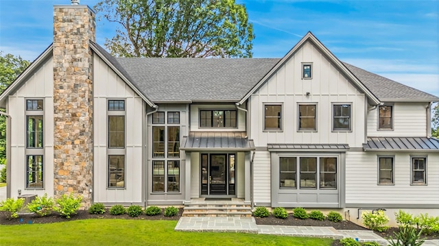 23 Sylvan Rd, Rye Brook, NY 10573 - back of house featuring a standing seam roof, a shingled roof, board and batten siding, a metal roof, and a chimney