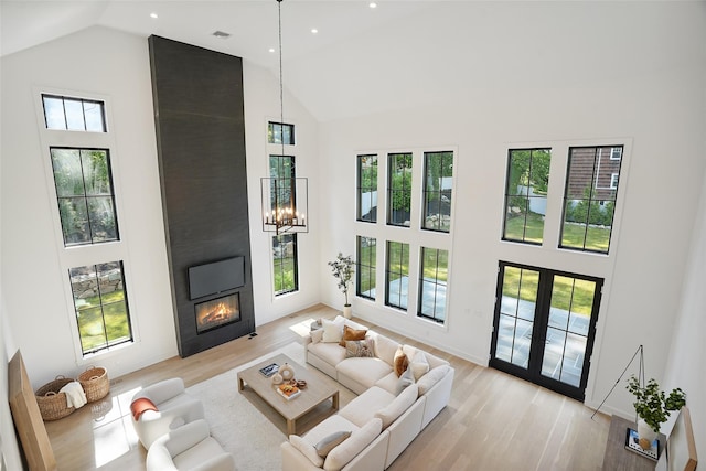 23 Sylvan Rd, Rye Brook, NY 10573 - living room featuring high vaulted ceiling, a large fireplace, healthy amount of natural light, light wood finished floors, and a chandelier