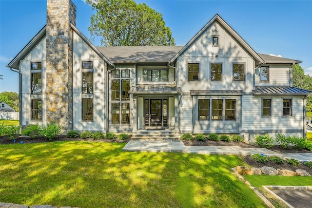 23 Sylvan Rd, Rye Brook, NY 10573 - back of property featuring a standing seam roof, a yard, a chimney, board and batten siding, and a metal roof