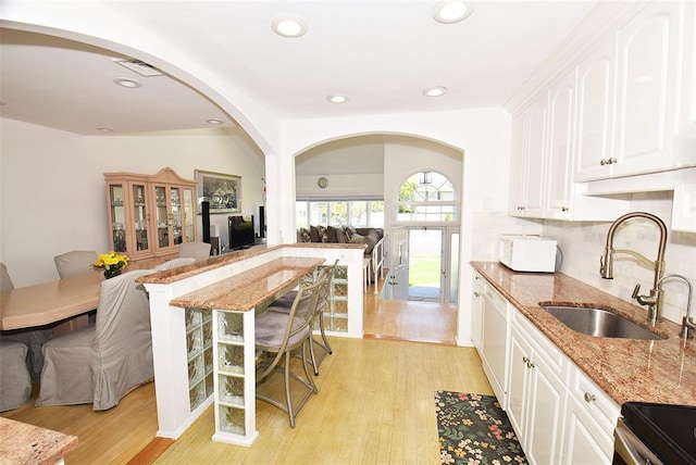 38 Loretta Dr, Syosset, NY 11791 - kitchen featuring white microwave, light stone counters, arched walkways, light wood-style floors, and recessed lighting
