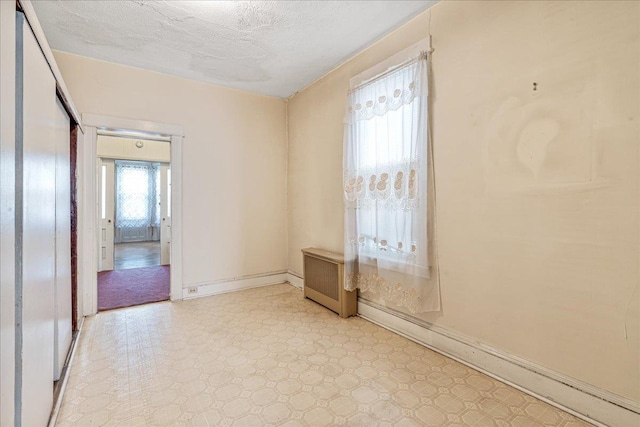 59-30 70th Ave, Ridgewood, NY 11385 - empty room featuring a baseboard radiator, light floors, radiator heating unit, and a textured ceiling