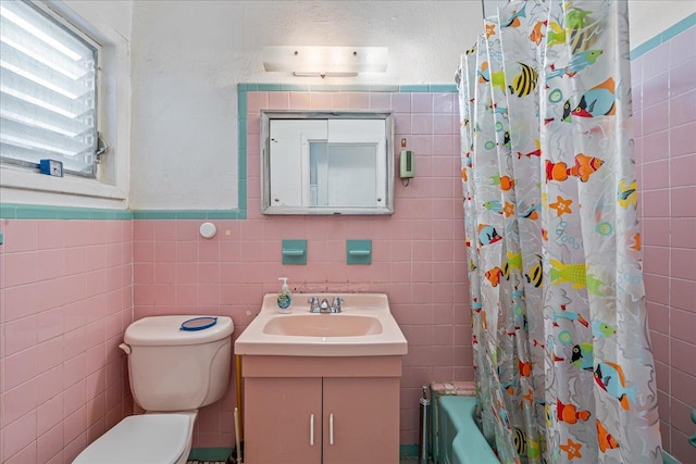 59-30 70th Ave, Ridgewood, NY 11385 - full bathroom featuring tile walls, vanity, shower / tub combo, and a wainscoted wall