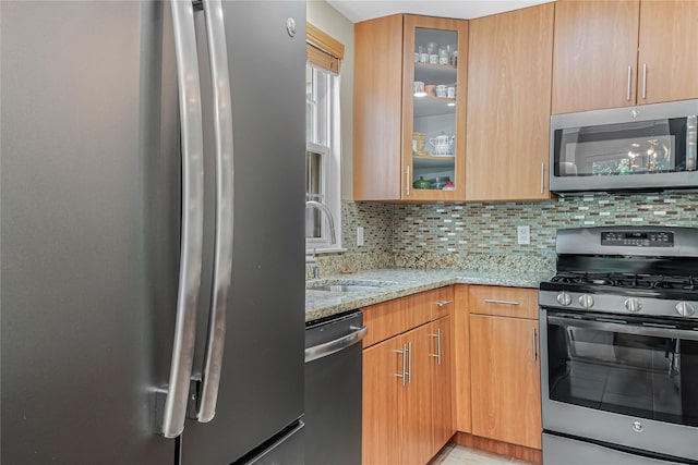55 Oceana Dr E Unit 1B, Brooklyn, NY 11235 - kitchen with appliances with stainless steel finishes, light stone counters, backsplash, and glass insert cabinets