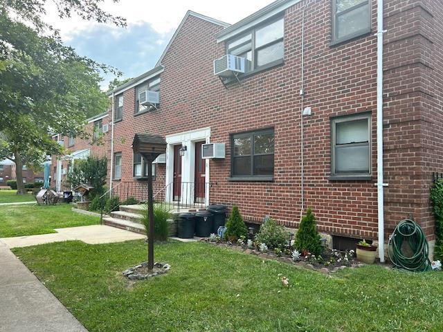 199-39 19th Ave Upper, Upper, Whitestone, NY 11357 - view of front of house featuring a front yard, brick siding, and an AC wall unit
