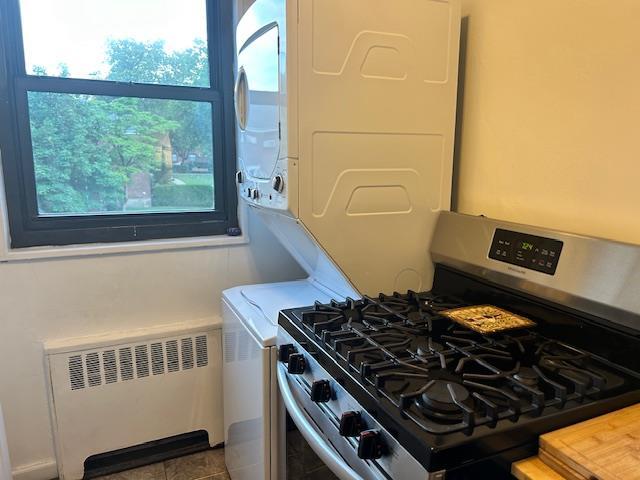 199-39 19th Ave Upper, Upper, Whitestone, NY 11357 - kitchen with stainless steel range with gas stovetop, radiator heating unit, stacked washing machine and dryer, and light countertops