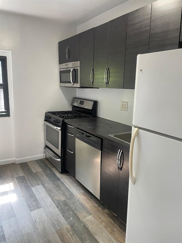 782 Cauldwell Ave, Bronx, NY 10456 - kitchen featuring stainless steel appliances, light wood-type flooring, dark countertops, and dark cabinetry