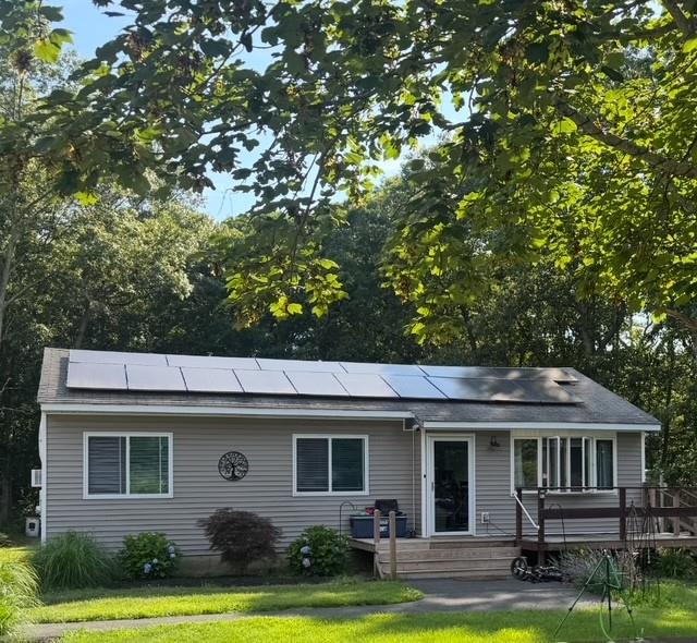 323 Doctors Path, Riverhead, NY 11901 - view of front facade featuring a wooden deck, solar panels, and a front lawn