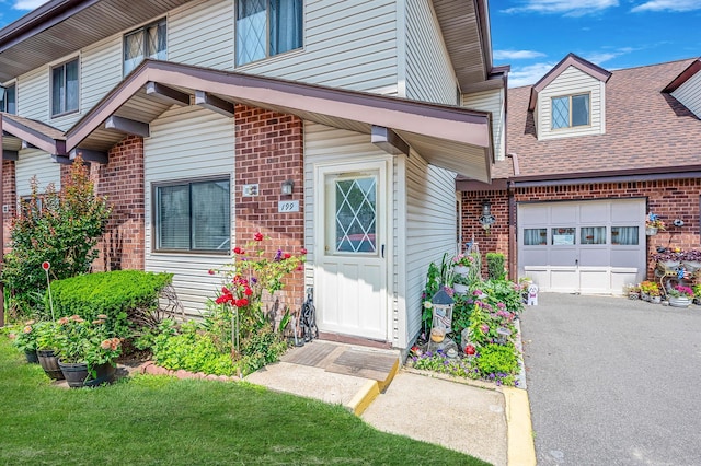 199 Cambridge Dr E, Copiague, NY 11726 - view of exterior entry with brick siding, a garage, asphalt driveway, and roof with shingles