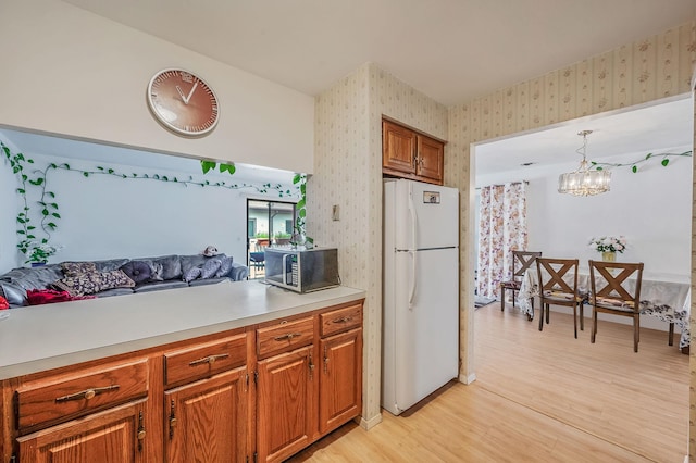 199 Cambridge Dr E, Copiague, NY 11726 - kitchen featuring freestanding refrigerator, wallpapered walls, stainless steel microwave, light wood finished floors, and brown cabinets