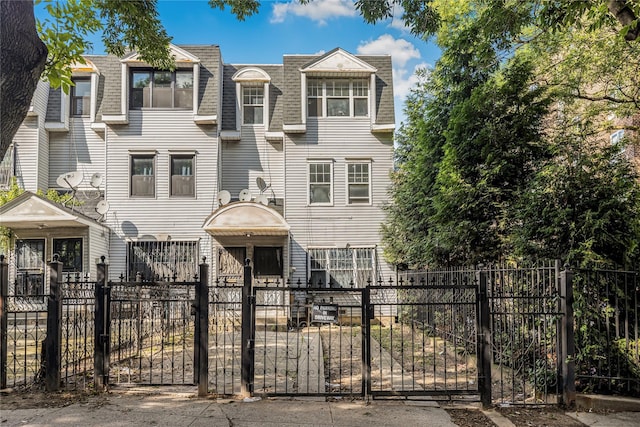 975 E 178th St, Bronx, NY 10460 - view of front of house with a shingled roof, mansard roof, a gate, and a fenced front yard