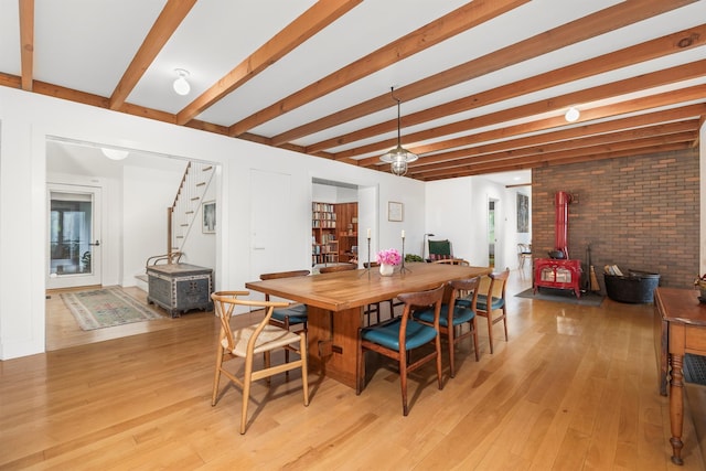 3778 State Route 82, Ancramdale, NY 12503 - dining space with a wood stove, stairs, light wood-style flooring, beamed ceiling, and brick wall