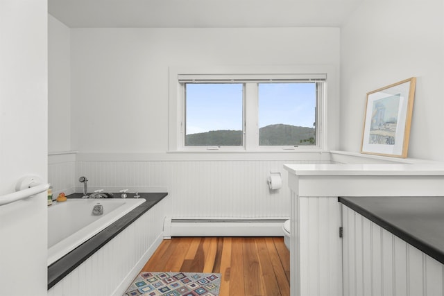 3778 State Route 82, Ancramdale, NY 12503 - bathroom featuring a baseboard radiator, wainscoting, wood finished floors, and a garden tub